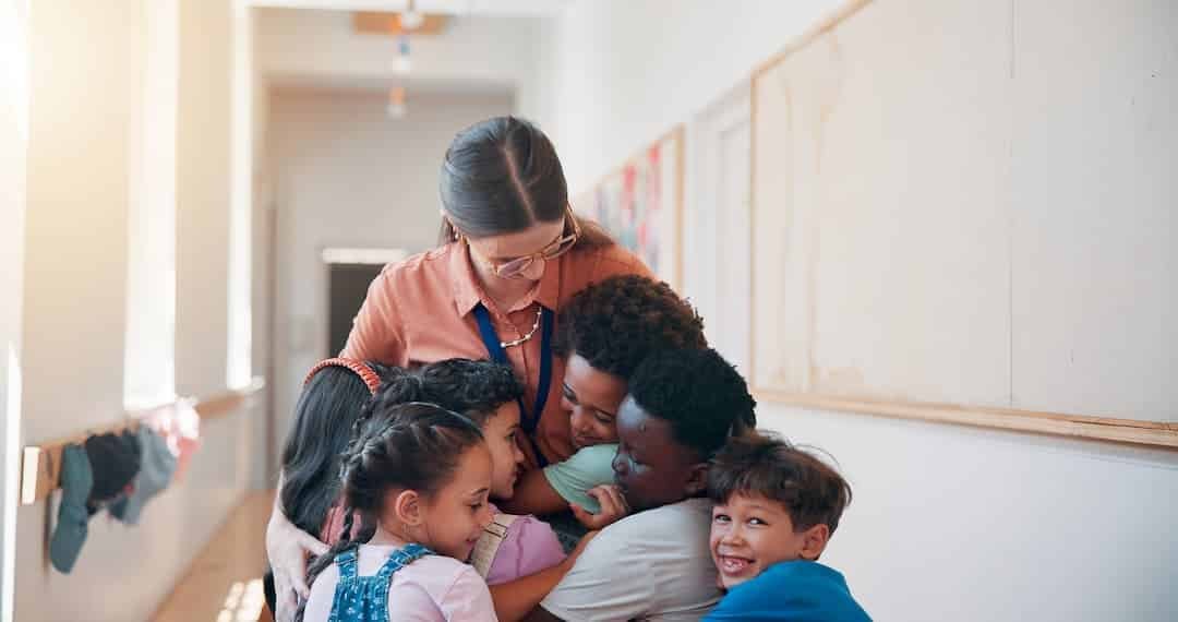School care and children hugging teacher and bonding